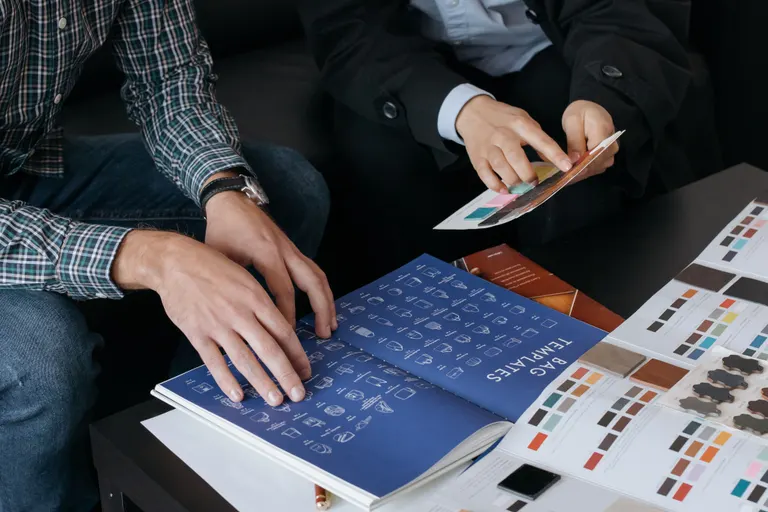 Two designers comparing typeface specimens and swatches at a studio desk